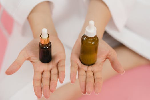 Close-up of hands holding two cosmetic dropper bottles for skincare routine.